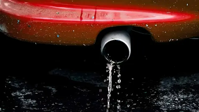 قطرات آب در حال خروج از لوله اگزوز یک خودروی قرمز رنگ