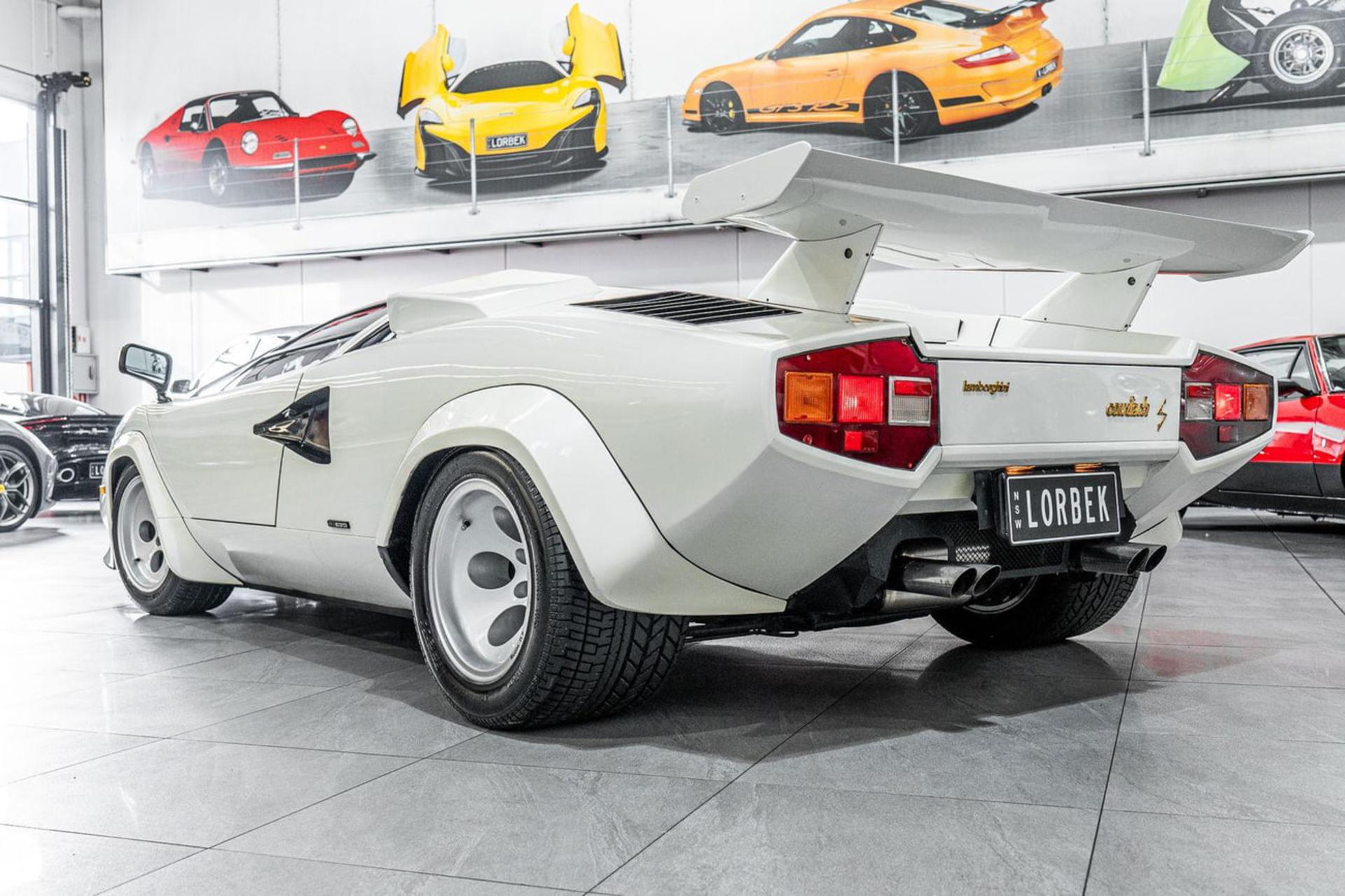 خودروی سفید لامبورگینی کنت (Lamborghini Countach) با بال عقب بزرگ در نمایشگاه