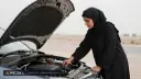 خانم راننده‌ای در حال بررسی سطح روغن موتور خودرو با استفاده از چوب مخصوص