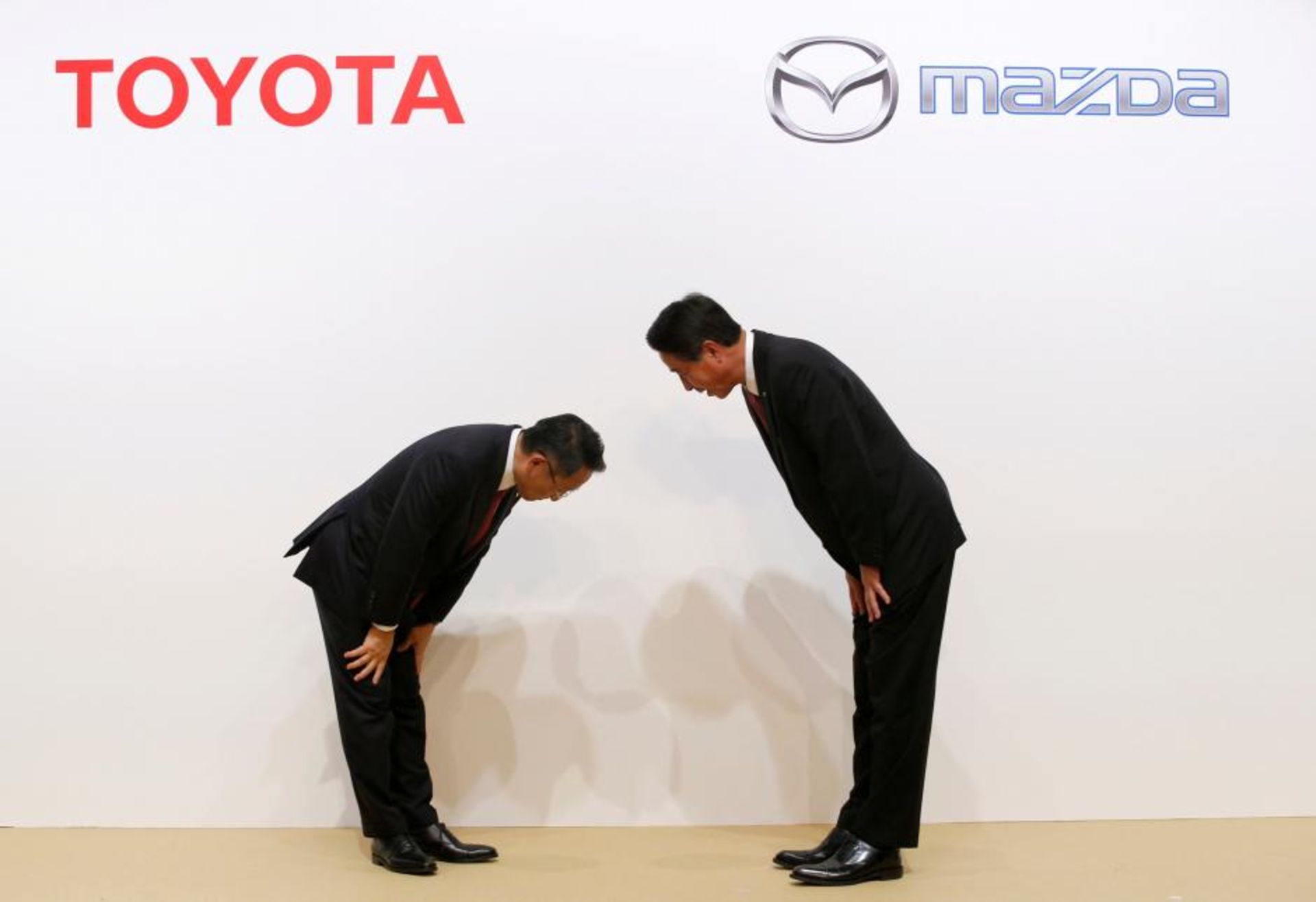 Toyota Motor President Akio Toyoda and Mazda Motor President Masamichi Kogai bow at a joint news conference in Tokyo
