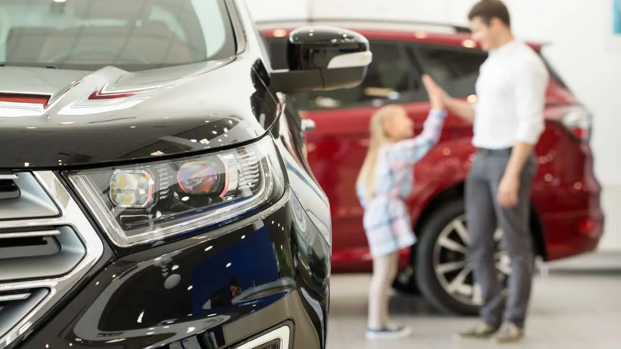 little-girl-high-fiving-her-father-on-the-showroom-floor-of-a-dealership