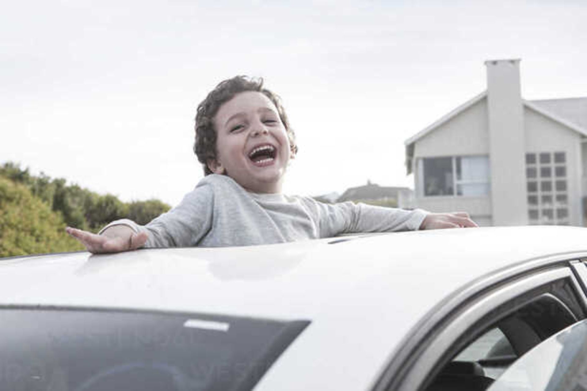 Happy boy looking through a sunroof of a car