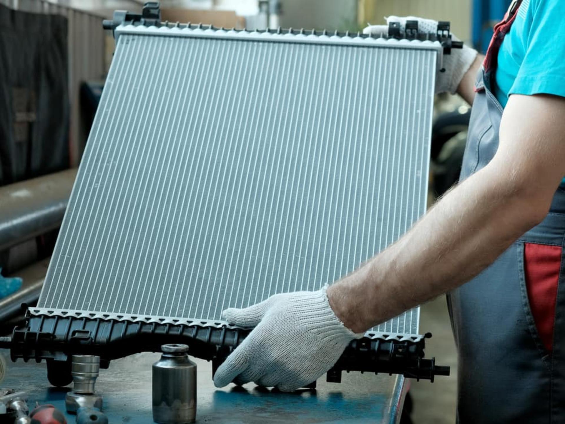 Mans-Gloved-Hands-Holding-a-New-Car-Radiator